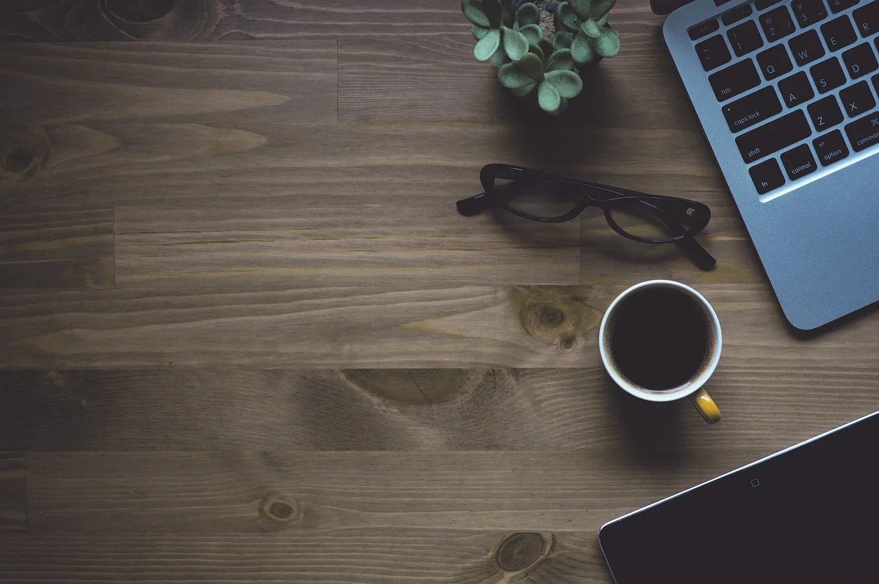 Laptop on a desk with a coffee cup and notebook, representing workspace technology and AI software integration